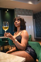 Vertical photo of a african young expertise tasting wine in a fine luxury restaurant