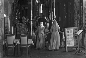 Women with robes in the historic arcades at the harbour, Genoa, Italy, Europe