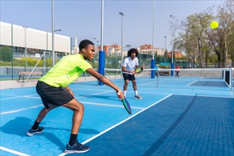 Side view full length photo of two african american young male friends having fun during pickleball