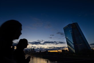 Two passers-by look over to the European Central Bank (ECB) in Frankfurt am Main in the evening,