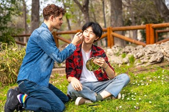 Smiling multi-ethnic gay couple making up sitting together in a park