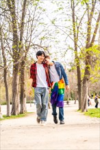 Vertical full length photo of a Romantic gay couple strolling in a park