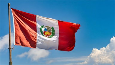 The flag of Peru flutters in the wind, isolated against a blue sky