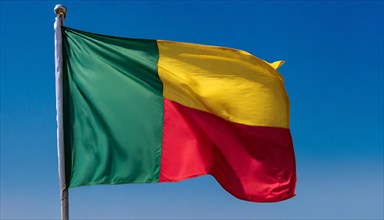 The flag of Benin flutters in the wind, isolated against the blue sky