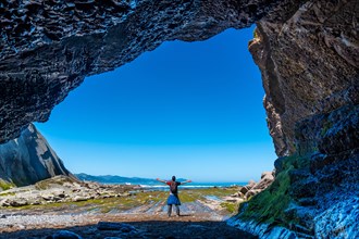 A hiker in the Algorri cove sea cave on the coast in the flysch of Zumaia, Gipuzkoa. Basque Country