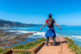 A tourist hiker visiting the Flysch Basque Coast geopark in Zumaia at the Algorri Viewpoint,