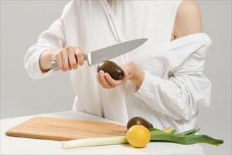 Unrecognizable woman cutting fresh avocado into halves. Concept of balanced eating