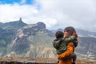 A mother with her son looking at Roque Nublo from a viewpoint. Gran Canaria, Spain, Europe