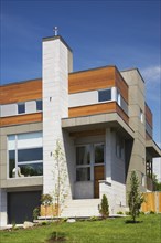 Two story grey and charcoal stone with cedar wood siding modern cube style home facade in summer,