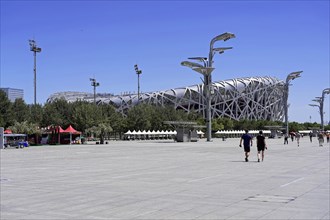 Beijing, China, Asia, Spacious forecourt of a modern stadium with people under a clear blue sky,