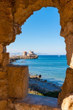 View of the bay of Rhodes through a window in a rock wall. In the background, the sea and the