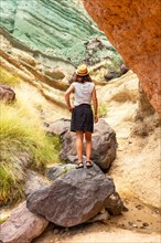 A tourist woman with a hat at the Azulejos de Veneguera or Rainbow Rocks in Mogan, Gran Canaria