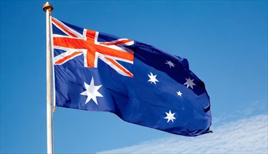 The flag of Australia flutters in the wind, isolated against a blue sky