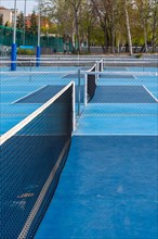 Vertical photo of empty several pickleball outdoor courts with net
