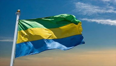The flag of Gabon, fluttering in the wind, isolated, against the blue sky