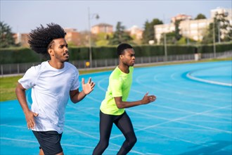 Side view with copy space of two young african sportsmen running along a athletics track