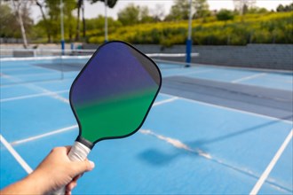 Close-up of a hand holding pickleball racket in an outdoor court