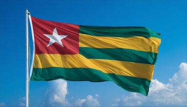 The flag of Togo flutters in the wind, isolated against a blue sky