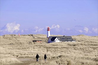 Sylt, Schleswig-Holstein, Two people walking towards a lighthouse with neighbouring houses on the