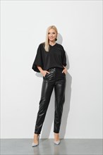 Pretty smiling blonde woman in black blouse and leather trousers