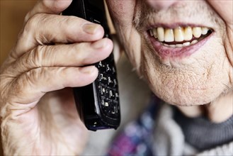 Mouth, hands and telephone receiver of a senior citizen making a phone call, close-up, Cologne,
