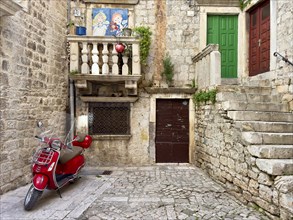 Red Vespa in front of the entrance of an old stone house, Trogir, Dalmatia, Croatia, Europe