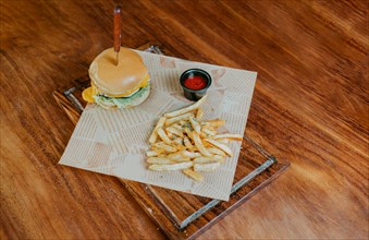 Top view of cheeseburger with french fries served on wooden table. Delicious hamburger with french