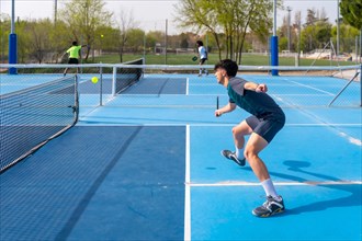 Sportive young man playing pickleball under the sun in an outdoor court