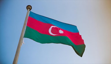 The flag of Azerbaijan flutters in the wind, isolated against a blue sky