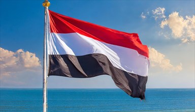 The flag of Yemen, fluttering in the wind, isolated, against the blue sky