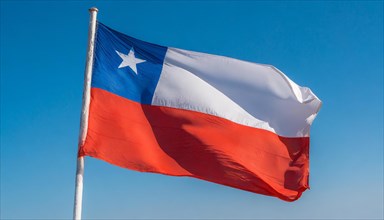 The flag of Chile flutters in the wind, isolated against a blue sky