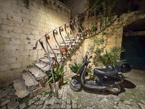 An old staircase with an abandoned scooter in a nocturnal setting, Trogir, Dalmatia, Croatia,