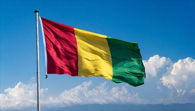 The flag of Guinea, fluttering in the wind, isolated, against the blue sky