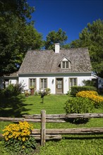 Old circa 1886 white with beige and brown trim Canadiana cottage style home facade with landscaped