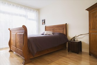 Antique wooden queen size sleigh bed in master bedroom inside a renovated ground floor apartment in