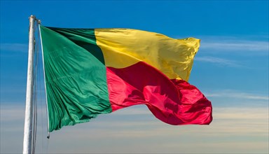 The flag of Benin flutters in the wind, isolated against the blue sky