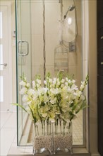 Silk flowers in front of clear glass shower stall in bathroom inside a renovated ground floor