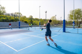 Full length of men playing pickleball in an outdoor court