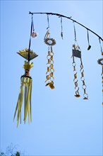 Ornate jewellery woven from palm leaves on bamboo poles, on a village street in Amed, Karangasem,