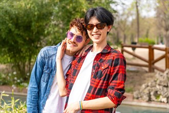 Portrait of a multi-ethnic gay couple smiling at camera standing together in a park