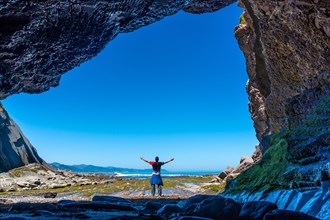 Man hiker in the Algorri cove sea cave on the flysch coast of Zumaia, Gipuzkoa. Basque Country