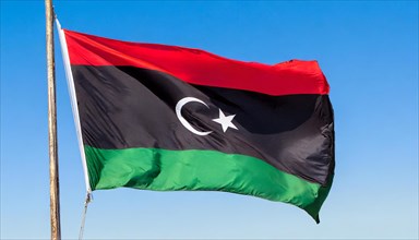 The flag of Libya, fluttering in the wind, isolated, against the blue sky
