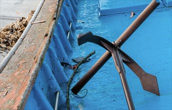 Metal anchor laying on deck of blue fishing boat in South Korea