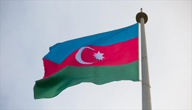 The flag of Azerbaijan flutters in the wind, isolated against a blue sky