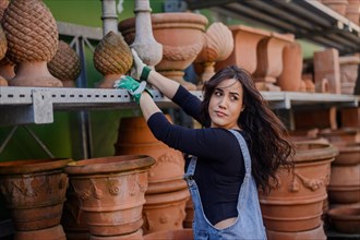 Woman engaging with terracotta pots in a pottery shop environment