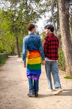 Vertical full length rear view of gay couple walking along a park