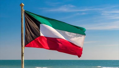 The flag of Kuwait flutters in the wind, isolated against a blue sky