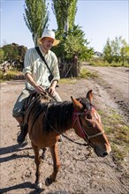 Young man on a horse, tourist riding, Bokonbayevo, Issyk Kul region, Kyrgyzstan, Asia