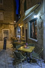 Empty cafe with tables on a cobblestone path at night, Trogir, Dalmatia, Croatia, Europe