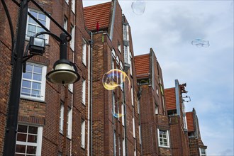 Shimmering soap bubbles rise into the sky in front of Rostock University on Universitaetsplatz,